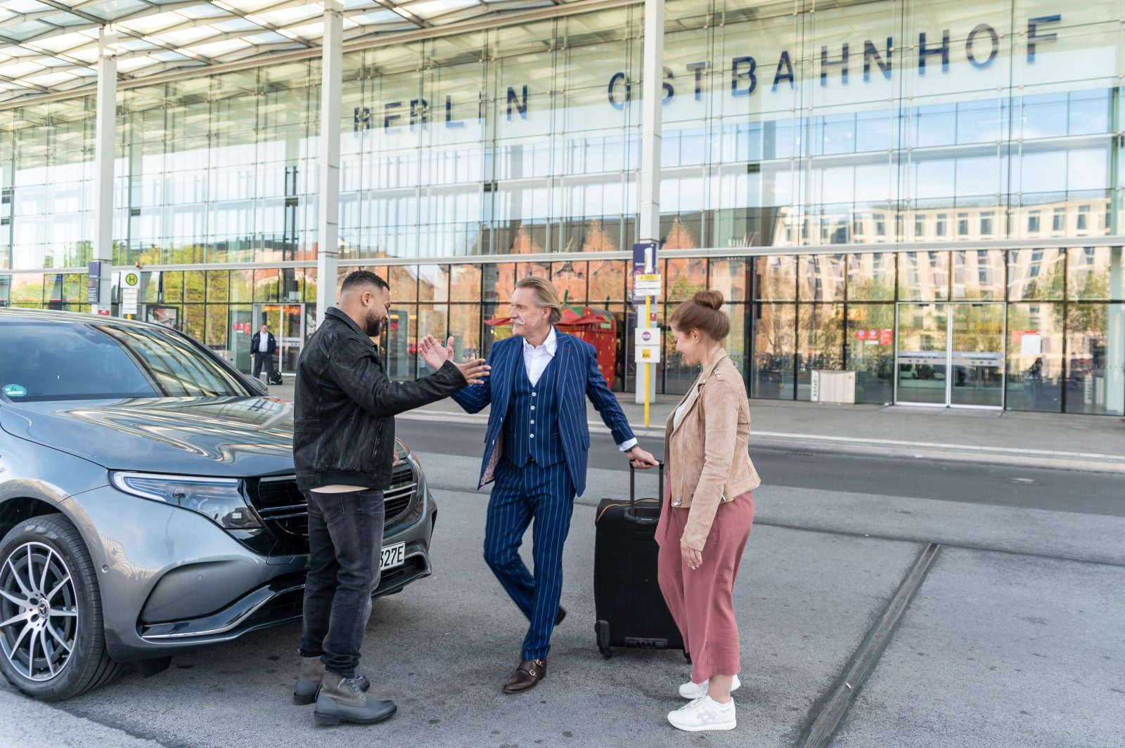 Ingo Lenßen wird von seinen Kolleg:innen Ben Handke (Marvin Ahmed-Johnson) und Sarah Grüner (Jessica Mechergui) zum Dreh der neuen Staffel am Ostbahnhof empfangen 