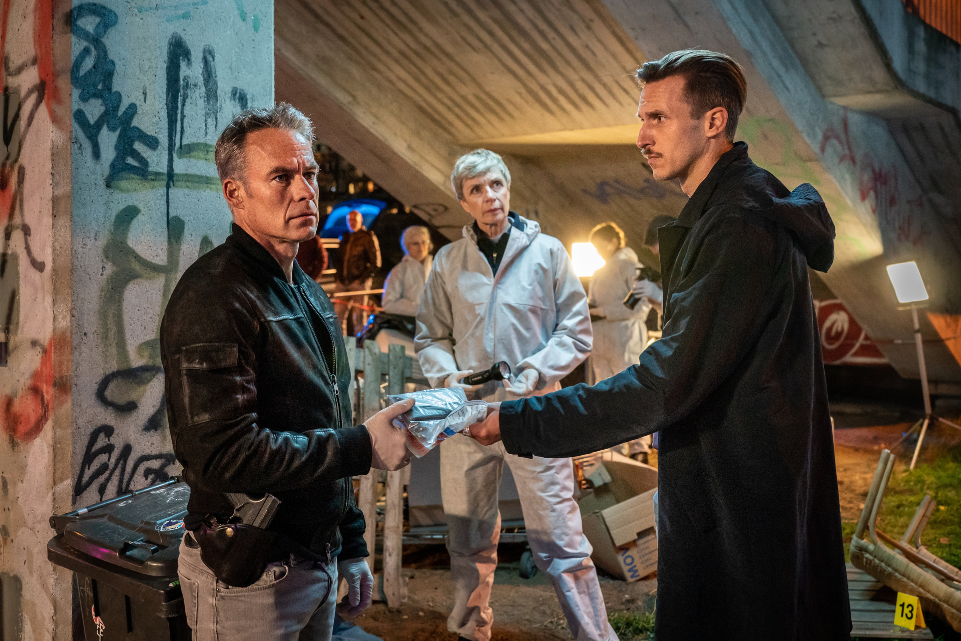 DIREKT INS HERZ (v.l.n.r.): Jan Maybach (Marco Girnth), Prof. Rossi (Anna Stieblich), Moritz Brenner (Johannes Hendrik Langer) und Mitarbeiter der Spurensicherung untersuchen den Tatort, der in unmittelbarer Nähe zu einem Straßenstrich liegt.